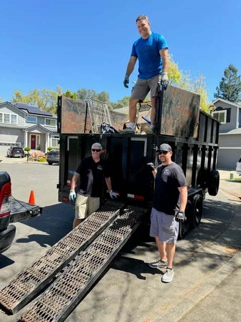 Three Big Trailer Services crew members beside a dump trailer